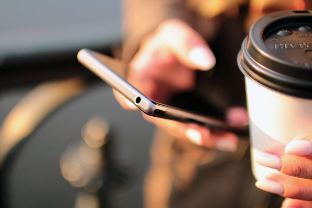 Manos sosteniendo smartphone con café - billetera digital BCRA medidas seguridad datos del titular agosto 2026