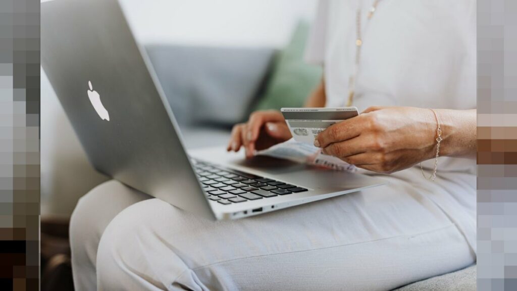 Persona sosteniendo tarjeta de crédito frente a laptop - e-skimming fraude compra online Argentina