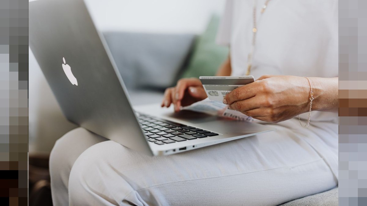 Persona sosteniendo tarjeta de crédito frente a laptop - e-skimming fraude compra online Argentina