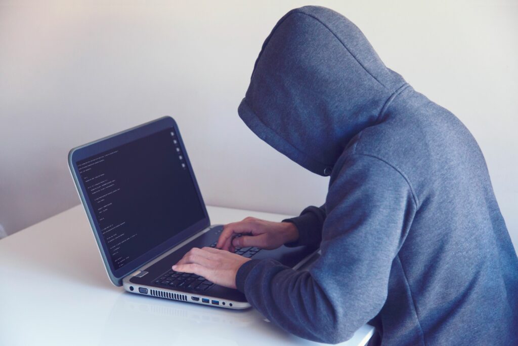 Persona con capucha frente a una laptop representando una estafa virtual o phishing bancario